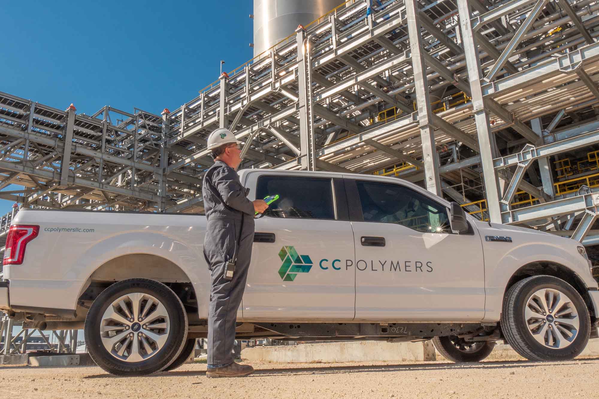 Showing a pickup truck with the CC Polymers logo and worker wearing overalls.
