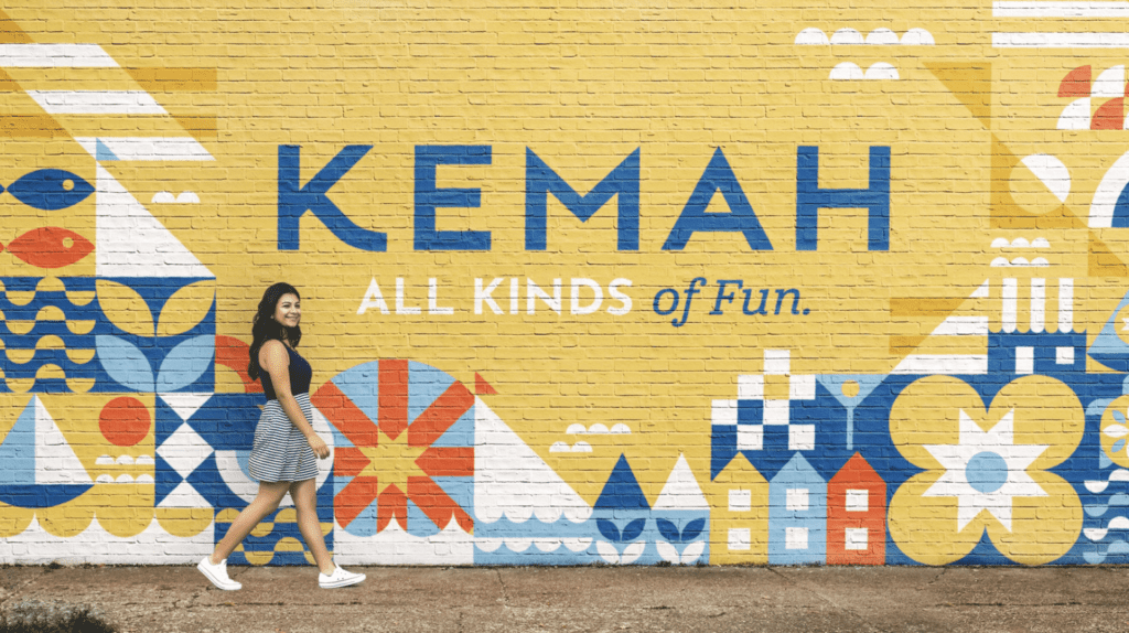 Showing the Kemah, TX wall mural with a girl walking in front of it.