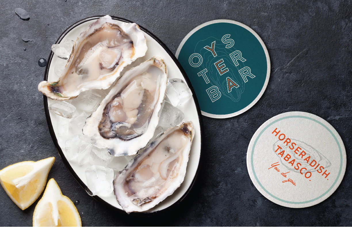 Showing some raw oysters served with cut lemons alongside coasters for the Oyster Bar. Branding designed by MDR.
