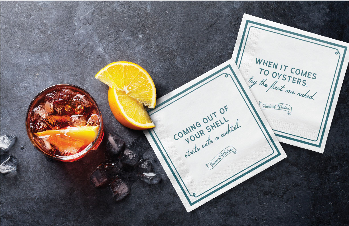 Showing Oyster Bar branded napkins next to a whiskey cocktail with orange slices. Designed by MDR.