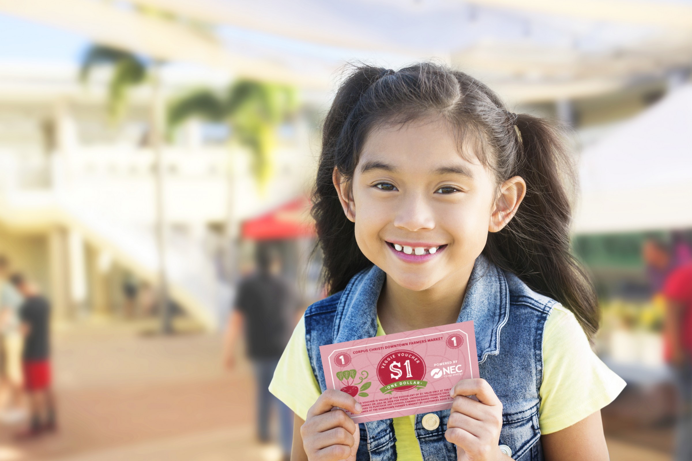 Showing a little girl holding the Farmer's Market veggie voucher.